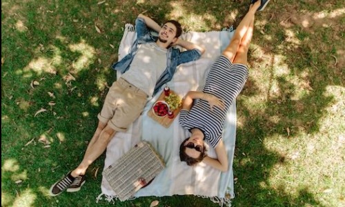 A couple laying under a shady tree enjoying a picnic