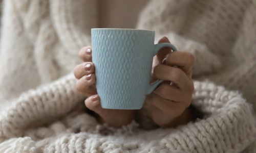 Woman holding mug wrapped in a blanket